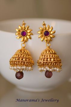 Grand and beautiful metal work jhumka earrings! The body of the jhumka sports a grand and intricate metal work, while the post of the earrings has a simple sun emblem with a pinkish purple kundan stone studded in the center. A cluster of small white pearls dangle from the rim.  A light colored purple stone hangs from the jhumka amongst a cluster of white beads. Earrings measure 2 3/4 inches (7 cm) in length. The earrings are made of copper metal with one gram gold plating. JEWELERY CARE INSTRUCT Wedding Jhumkas With Latkans, Wedding Drop Jhumkas With Latkans, Wedding Drop Jhumkas, Temple Jewelry Jhumkas With Latkans As Gift, Temple Jewelry Meenakari Drop Jhumkas, Navratri Latkans Jhumka Drop Earrings, Temple Jewelry Style Jhumkas For Navratri, Temple Jewelry Jhumkas For Navratri, Chandbali Jhumkas With Latkans For Puja