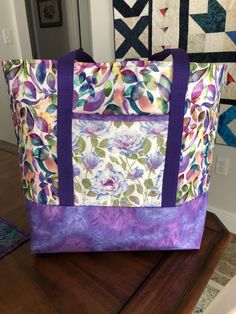 a colorful bag sitting on top of a wooden table next to a quilted wall hanging