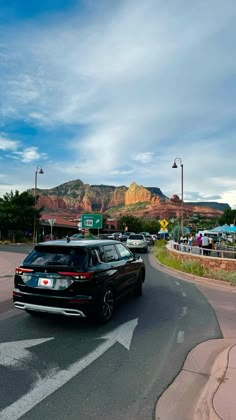 cars are driving down the road in front of mountains