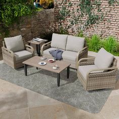 an outdoor living room with wicker furniture and brick wall in the backround