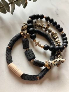 Get ready to add a touch of spiritual serenity to your everyday look with these stunning Boho stack bracelets, featuring the perfect fusion of matte Black Onyx and Dalmatian Jasper, delicately accented with gold details. Complete with a radiant rhinestone cross and empowering lava rock stone, this stack doubles as a stylish diffuser bracelet for your favorite essential oils. Simply put 1-2 drops of your favorite essential oil into each lava bead and enjoy the aroma for 24-48 hours. Each diffuser bracelet includes 3 lava stone beads. Essential oil is NOT included.   Crafted with elastic string, these bracelets offer a slight stretch for comfort, but are best rolled on and off individually when putting on or removing.  PLEASE MEASURE YOUR WRIST BEFORE ORDERING!  Add 1/2 inch for a more snug Bohemian Lava Stone Beaded Bracelets Gift, Bohemian Lava Stone Beaded Bracelet Gift, Bohemian Lava Stone Bracelets For Gift, Bohemian Lava Stone Bracelet As Gift, Black Bohemian Stretch Bracelet Stackable, Black Bohemian Stackable Stretch Bracelet, Bohemian Black Stackable Stretch Bracelet, Neutral Jewelry, African Bracelets