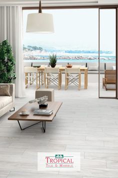 a living room filled with furniture next to a large glass door that leads out to the beach