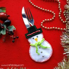 a snowman ornament with a fork and knife on a red place mat