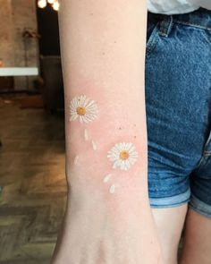 a woman's arm with two small white flowers on the left side of her arm