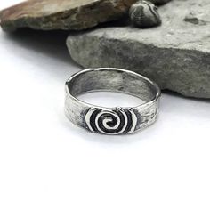 Description: SImple ring with softly textured band, center piece is a life spiral with a raised design. Available to ship Size: 4-14 I can size in whole, half or quarter sizes because we don't all fit perfectly in the whole sizes. Depending on the ring design, the design can change depending on the size. Made to order pieces - design will vary slightly from the photo, as each ring is handcrafted just for you! Specifications: Materials: Sterling silver Approximately width 6.25 mm Jewelry by Caria Adjustable Spiral Jewelry With Oxidized Finish, Unique Spiral Rings For Anniversary, Handmade Spiral Rings For Anniversary, Handmade Spiral Anniversary Rings, Hand Forged Spiral Ring As Gift, Hand Forged Spiral Ring For Gift, Hand Forged Silver Spiral Rings, Hand Forged Spiral Rings For Gifts, Hand Forged Spiral Ring