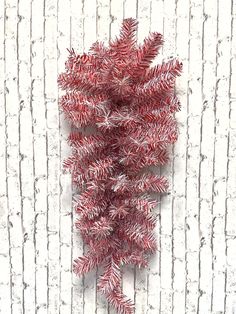 a bunch of red tinsel on top of a white brick wall next to a plant