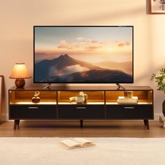 a flat screen tv sitting on top of a wooden entertainment center next to a lamp