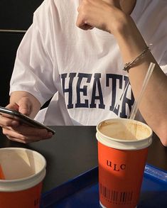 a person sitting at a table with a cup and cell phone in front of them