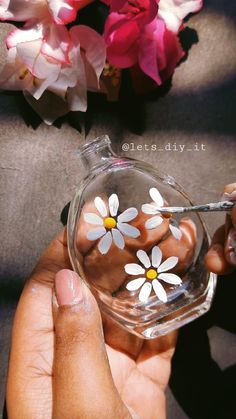 someone is painting flowers in a glass vase