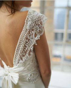 the back of a woman's wedding dress with beading and pearls on it