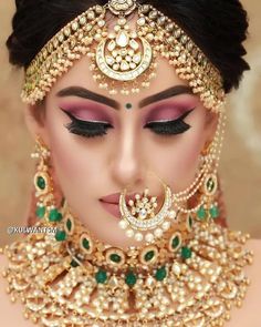 a woman wearing a gold and green bridal outfit with jewels on her head, nose ring