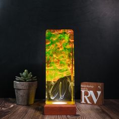 a glass vase sitting on top of a wooden table next to a potted plant