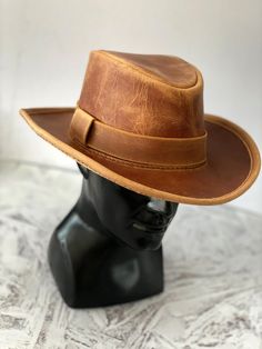 DESCRIPTION Channel your inner Indiana Jones with our Vintage Leather Outback Hat! Every hat is meticulously handcrafted using durable, waxed thread, ensuring it stands up to any adventure. Whether you're exploring ancient ruins or navigating the urban jungle, this hat is your trusty companion. Inspired by the iconic fedora, it's designed for those who crave excitement and discovery. Perfect for both men and women, this hat makes a fantastic gift for the adventurer in your life or anyone who adm Country Style Fedora With Flat Bill For Outdoor, Classic Brown Handmade Hat, Casual Brown Leather Hat, Country Style Brown Hat Bands For Outdoor, Brown Country Style Hat Band For Outdoor, Vintage Flat Brim Fedora For Travel, Vintage Brimmed Fedora For Travel, Vintage Brown Travel Hat, Rustic Brown Hat For Outdoor