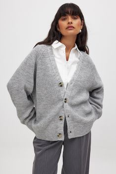 This cardigan features an oversized fit and a stretchy, soft knit material. It has a v neckline and a button closure down the front. Soft Knit V-neck Cardigan For Daywear, Cozy Gray V-neck Outerwear, Gray Knit Button-up Outerwear, Gray Knit V-neck Outerwear, Gray V-neck Knit Outerwear, Oversized Gray Knit Cardigan, Gray Knitted V-neck Outerwear, Gray Knit Sweater With Button Closure, Trendy Gray Buttoned Cardigan