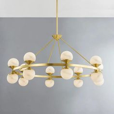 a chandelier hanging from the ceiling with white glass balls on it and gold fixtures