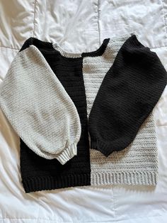 two black and white sweaters laying on top of a bed