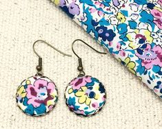 a pair of earrings sitting on top of a white floor next to a colorful tie