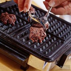 a person spooning some food on top of a waffle iron with a fork