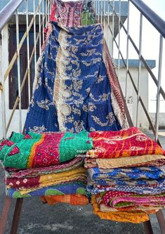 many colorful fabrics are stacked on top of each other in front of a stair case