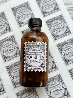 a brown bottle sitting on top of a table covered in postage stamps and paper with the words vanilla extract