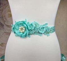 A great belt for wedding dress in aquamarine color, decorated with glass beads, acrylic beads, lace and flowers made of satin ribbon. The motif is 22 cm. long and embroidered in the middle 6 cm. wide hand.  The bridal belt is 2.5 cm. wide and total length 2.5 meters. The belt comes in a gift box, for better storage. Belt For Wedding Dress, Flower Belt, Aquamarine Colour, Wedding Sash Belt, Dragon Necklace, Wedding Belts, Bridal Belt, Lace Flower, Boho Bridal