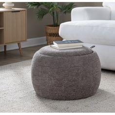 a living room with a white couch and book on top of the footstool