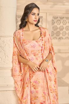 Peach kaftan style kurta with all-over floral prints and front pleats. Comes with matching floral printed, inverted pleated skirt. Paired with plain bustier and hand embroidered belt.
Components: 4
Pattern: Printed, Hand Embroidered
Type Of Work: Floral Patterns
Neckline: Kaftan: V Neck, Bustier: Sweetheart
Sleeve Type: Kaftan: Batwing, Bustier: Sleeveless
Fabric: Bustier: Modal Satin, Skirt and Kaftan: Chiffon
Color: Peach
Other Details: 
Tassel edged kaftan kurta
Back tie-up belt
Occasion: Meh Unstitched Peach Sets In Traditional Drape, Traditional Peach Dress With Drape, Unstitched Peach Sharara With Traditional Drape, Peach Designer Saree-style Dress, Designer Peach Dress With Traditional Drape, Peach Designer Saree Dress, Designer Peach Saree Dress, Peach Georgette Dupatta With Pallu, Traditional Peach Saree Dress