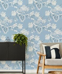 a blue floral wallpaper in a living room with a plant on the sideboard