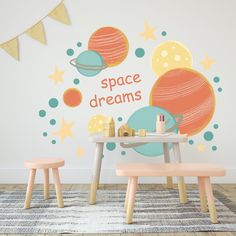 a child's room with space themed wall decals and wooden stools in front of the table