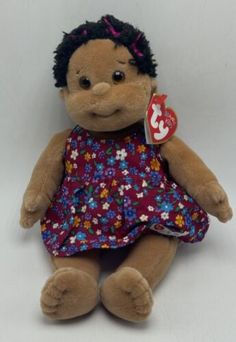 a brown teddy bear wearing a dress with flowers on it's chest and black hair