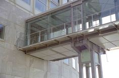 a clock on the side of a building with glass balconies and railings