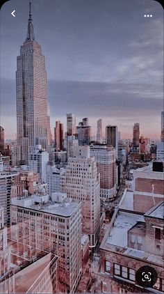 the city skyline is covered in pink and grey colors as the sun sets over skyscrapers