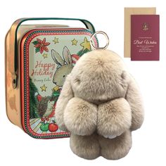 a teddy bear sitting in front of a tin with a holiday card on it's back