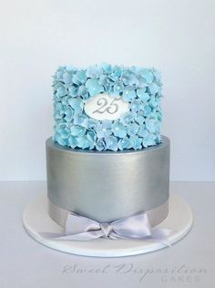 a silver and blue cake with flowers on top