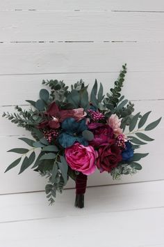 a bridal bouquet with pink and blue flowers on a white background, close up