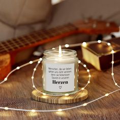 a candle that is sitting on top of a table next to some string lights and a guitar