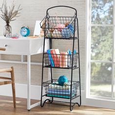 a three tiered shelf with baskets on it in front of a desk and window