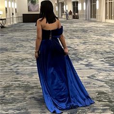 a woman in a blue dress is walking down the hall