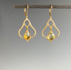 "Introducing our stunning Citrine earrings - the perfect accessory to add a touch of elegance to any outfit. Made with exquisite craftsmanship and attention to detail, these earrings showcase the beauty of the golden yellow Citrine stone. Crafted with high-quality materials, these earrings are designed to last, and their timeless style ensures they will never go out of fashion. The Citrine dangles within a Moroccan inspired shape of brushed Vermeil gold. The sparkling Citrine stone is set in a d Elegant Crystal Gemstone Earrings, Elegant Formal Citrine Earrings, Elegant Briolette Gemstone Chandelier Earrings, Elegant Crystal Drop Earrings With Gemstone, Elegant Teardrop Gemstone Chandelier Earrings, Elegant Teardrop Chandelier Earrings With Gemstone Accents, Elegant Yellow Gold Chandelier Earrings With Gemstones, Elegant Gold Faceted Crystal Earrings, Yellow Gemstone Earrings For Wedding