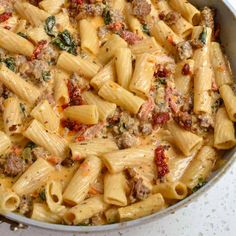 pasta with sausage and spinach in a pan on the stove top, ready to be cooked