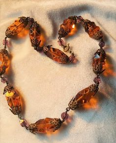 I just love brass and glass necklaces. They are so ornate and really lovely. This one is 17 inches long. The orangey gold glass beads ae 1 inch long by just under 1/2 inch wide. They are capped by filigree brass caps and interspaced with purple beads. The orange beads are cut like cubist style, very art deco. C. 1930 and Czech. Follow me on instagram@jettesjewels. Vintage Czech Glass Beaded Necklaces With Polished Beads, Vintage Czech Glass Beaded Necklace, Vintage Brass Beaded Necklace With Round Beads, Vintage Bronze Beaded Necklace With Large Beads, Vintage Bronze Beaded Necklaces With Large Beads, Vintage Amber Jewelry With Large Beads, Vintage Czech Glass Polished Beads Necklace, Vintage Czech Glass Necklace With Polished Beads, Vintage Czech Glass Necklaces With Polished Beads