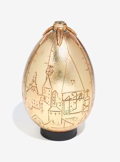 an egg shaped vase is sitting on a white surface with buildings drawn on the side