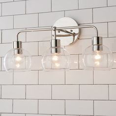 three clear glass globe lights on a white brick wall mounted vanity light fixture in a bathroom