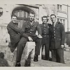 four men in uniforms are posing for a photo on the steps outside an old building