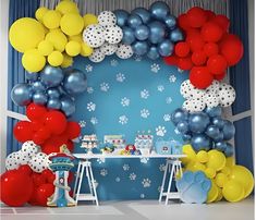 a birthday party with balloons and paw prints on the wall, blue curtains, and white table cloths