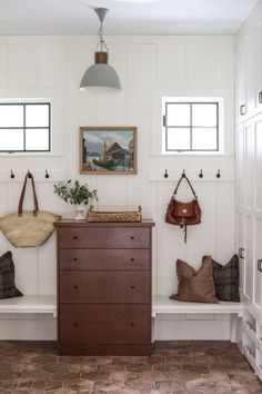 a room that has some bags on the wall and a dresser in front of it