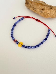 - This minimalist adjustable bracelet features vibrant blue-striped glass seed beads, a striking red cord, and a central red evil eye bead for protection and style. - Handcrafted with a delicate 925 silver charm, gold plated for a luxurious finish, this piece comes from the heart of Istanbul's artisan traditions. - Perfect for layering or wearing alone, this bracelet adds a touch of cultural elegance to your daily wear. A thoughtful gift or a unique accessory for those who appreciate high-qualit Meaningful Jewelry, Cord Bracelet, Christmas Gift Jewelry, Cord Bracelets, Gold Plated Silver, Handmade Artisan, Accessories Unique, Adjustable Bracelet, Artisan Jewelry