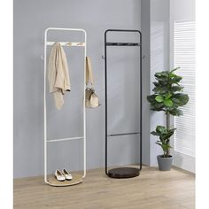 an ironing board and coat rack in the corner of a room with a potted plant