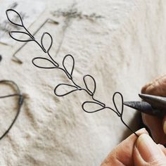 a person cutting wire with scissors on top of a piece of art that looks like a plant