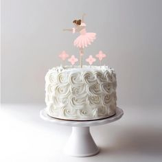 a white cake topped with a pink ballerina topper